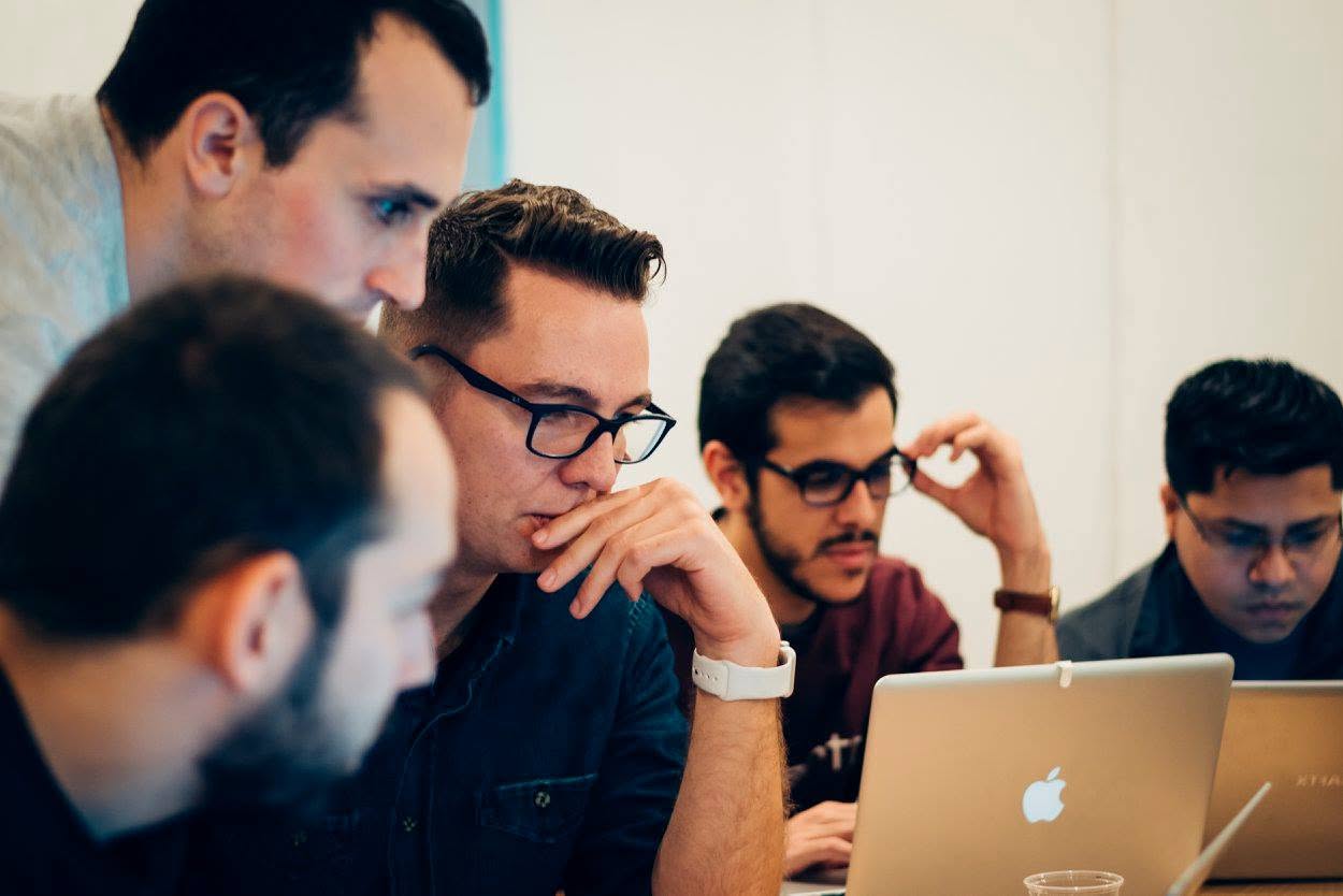 Teilnehmende schauen bei einem DevMeetings-Workshop gemeinsam auf einen Laptop