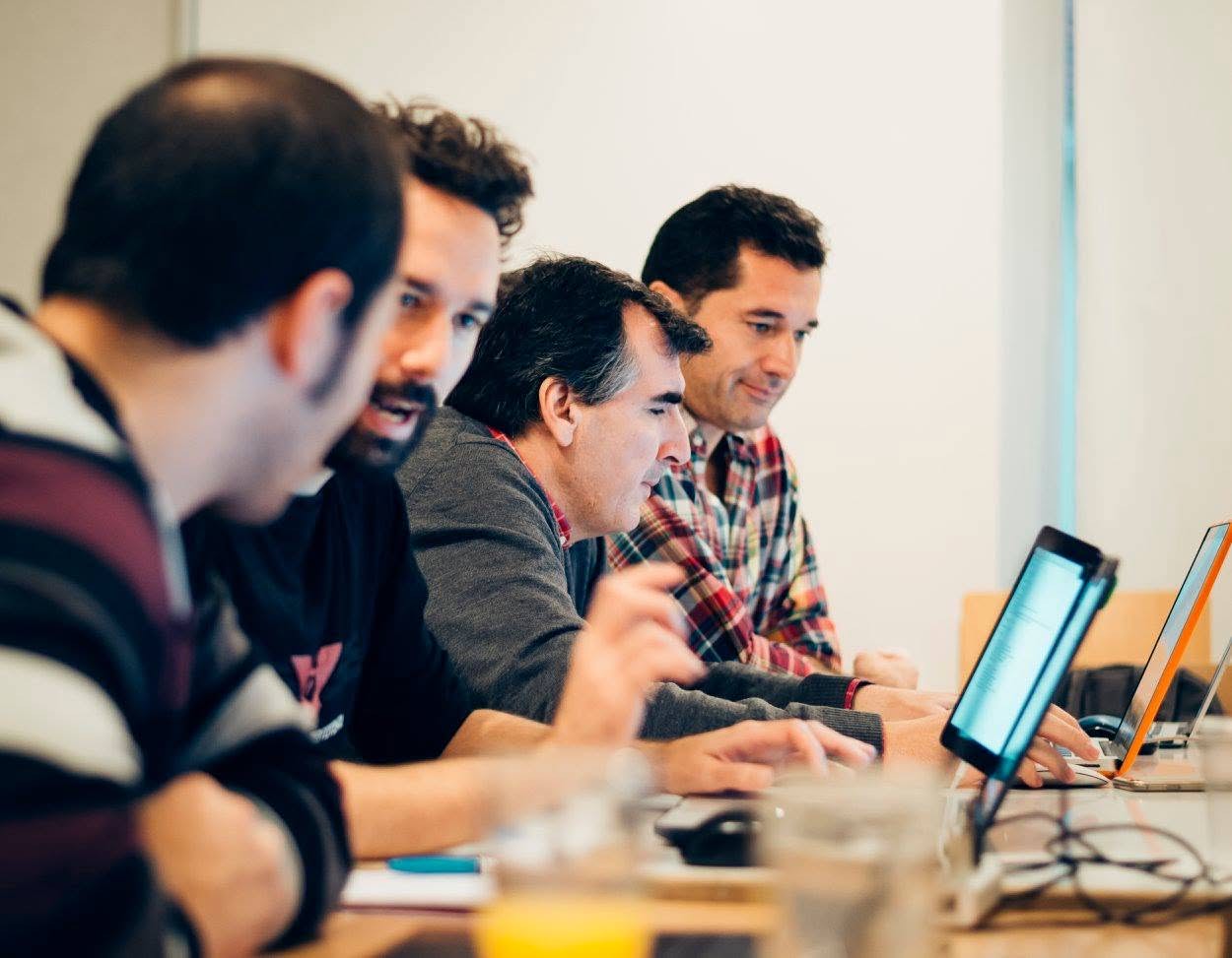 Teilnehmende arbeiten bei einem DevMeetings-Workshop gemeinsam an Laptops